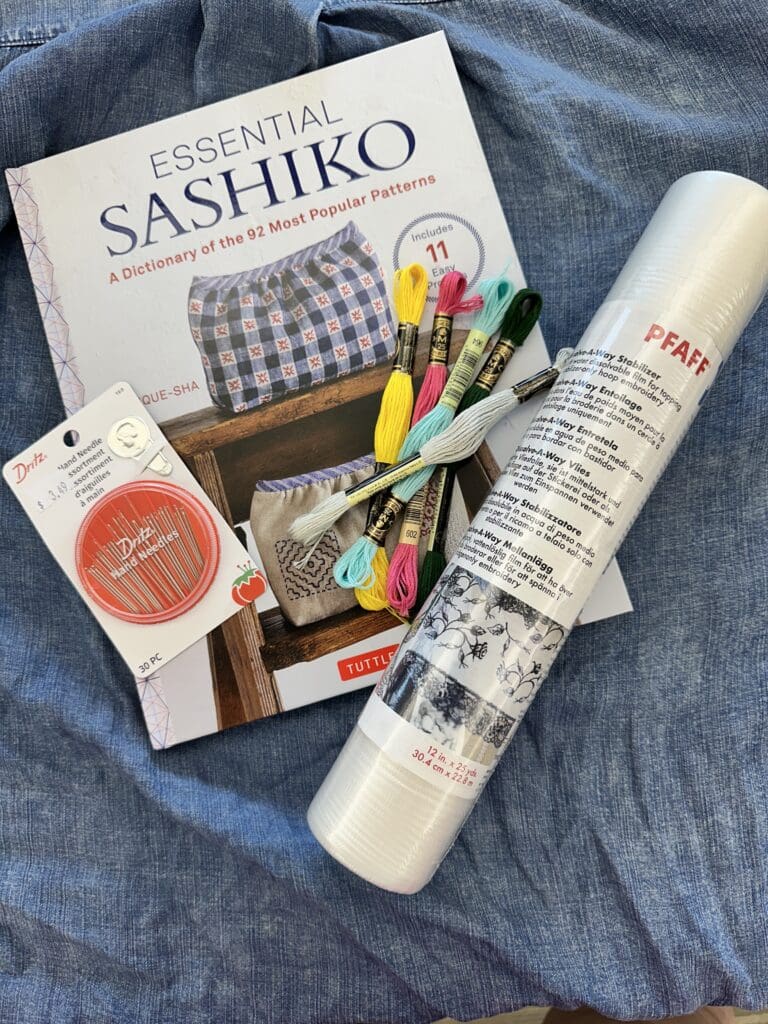 A Sashiko embroidery kit with needles, thread, and fabric essentials.