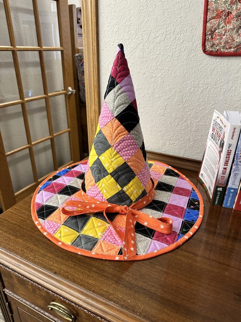Colorful quilted witch hat on table.