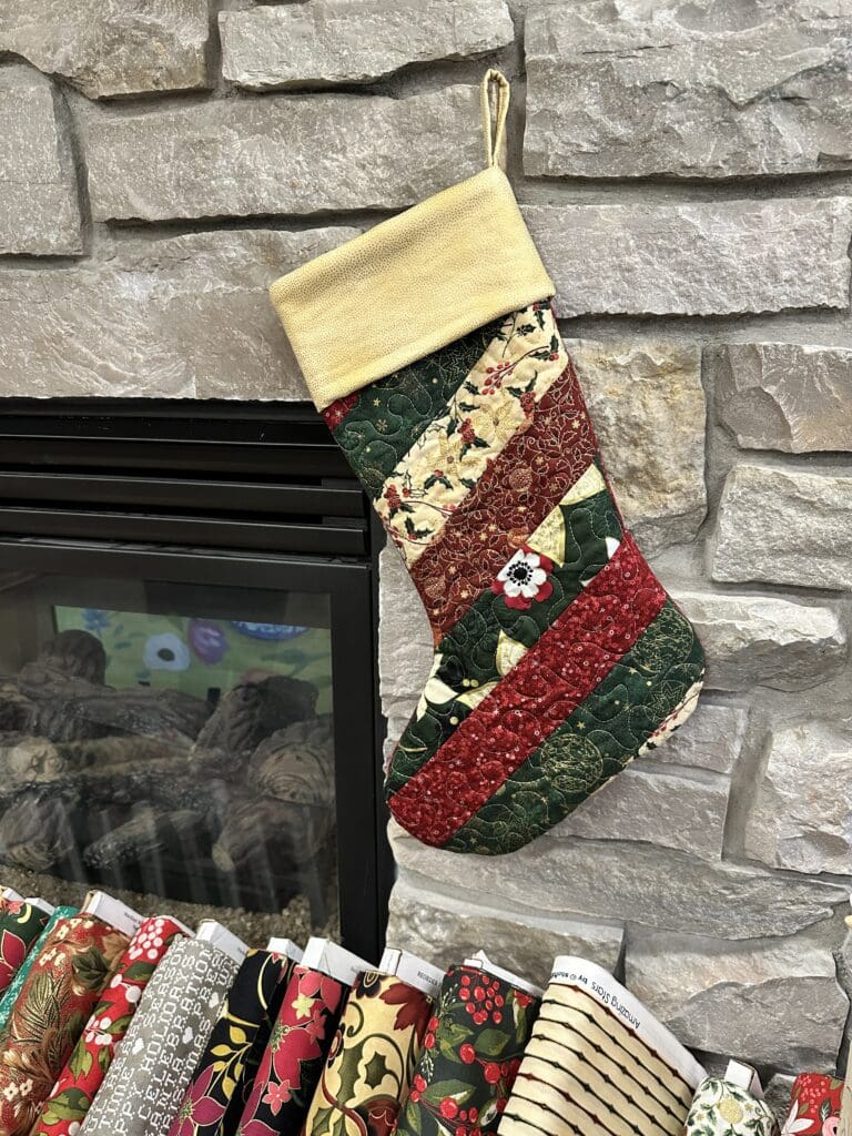 Quilted Christmas stocking hanging by fireplace.