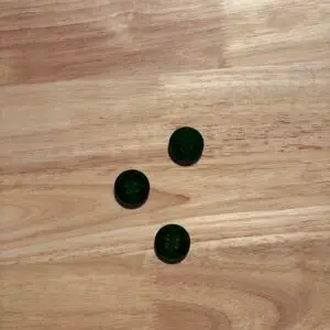 Three dark green buttons on wooden surface