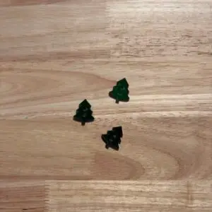 Three small green tree confetti on wood