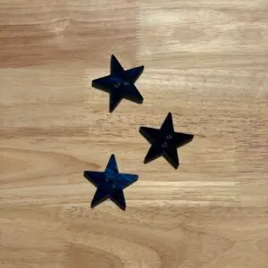 Three navy star-shaped buttons on wooden surface