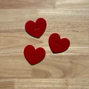 Three red heart-shaped buttons on wood