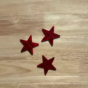 Three red star-shaped decorations on wooden surface