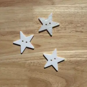 Three white star-shaped buttons on wood