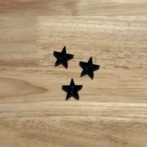 Three black star-shaped buttons on wood