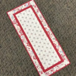 Red and white floral table runner on carpet