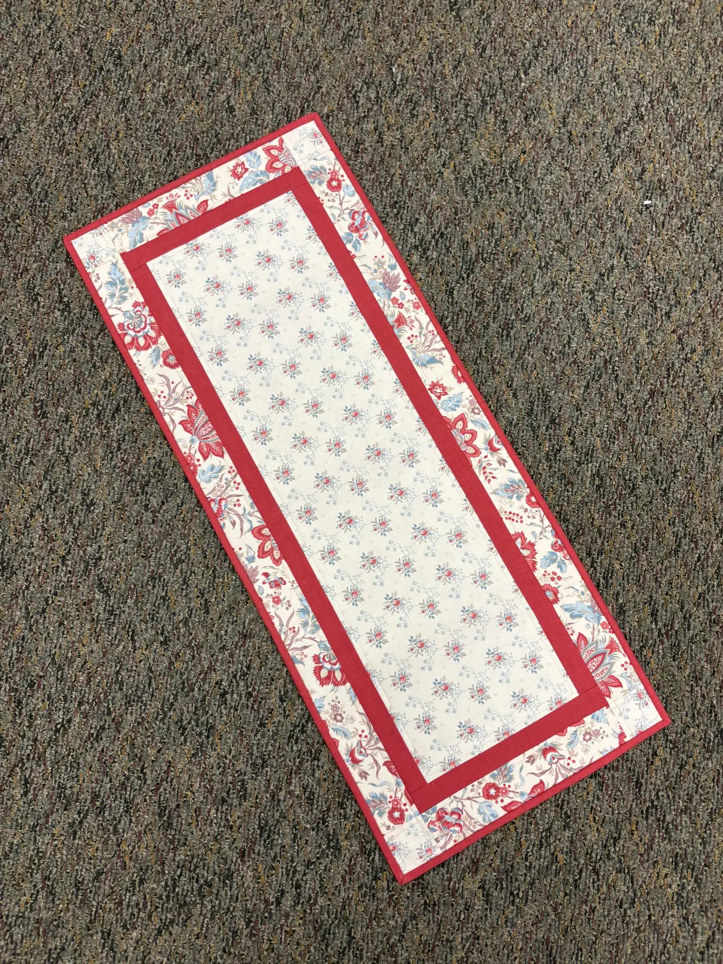 Red and white floral table runner on carpet